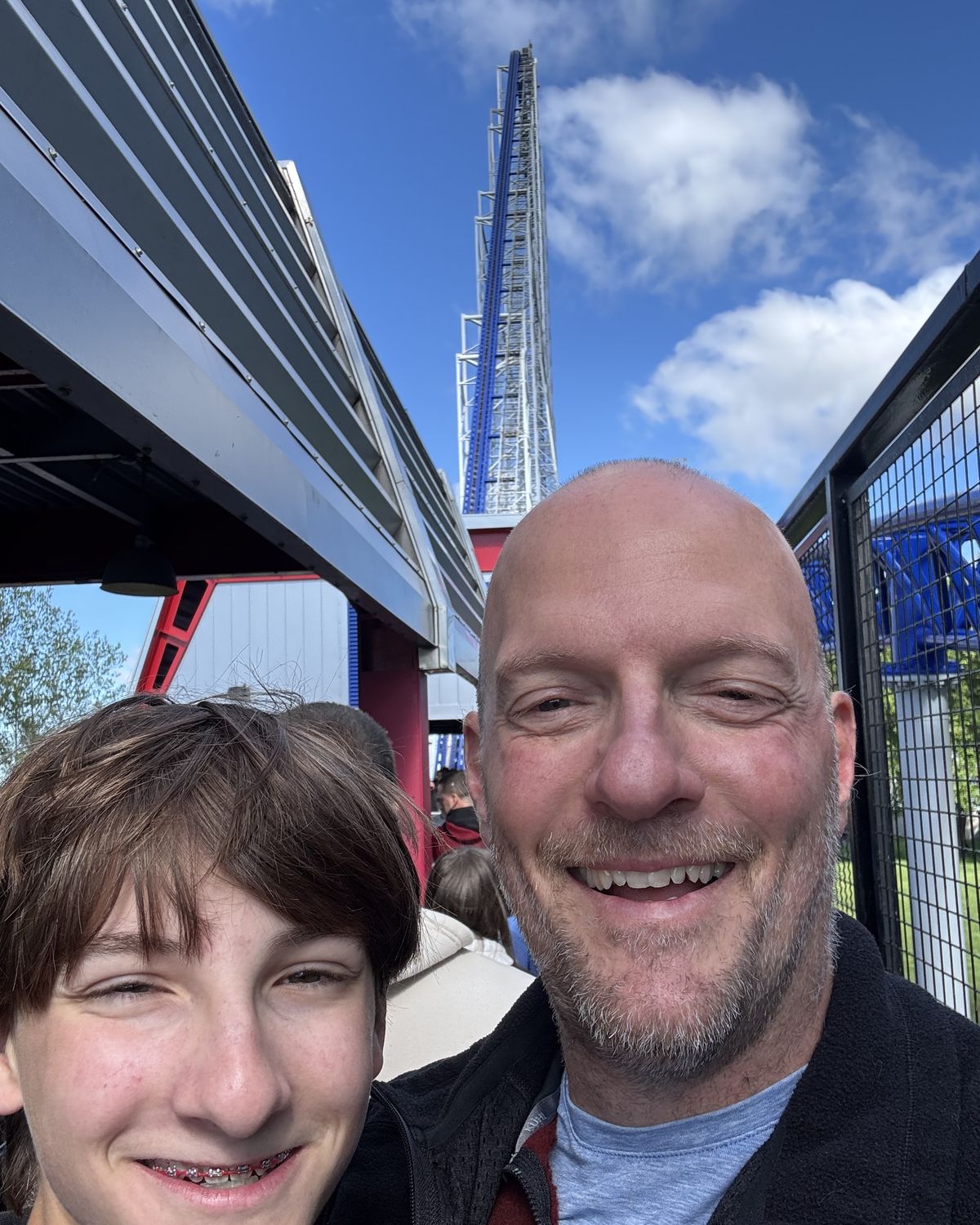 Aric and his son Ian at Cedar Point, with a roller coaster tower behind them.